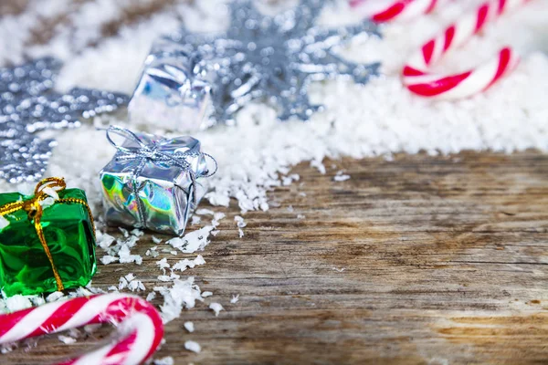 银色的雪花 礼物和糖果在雪地上的老褐色木背景 圣诞节边界 — 图库照片