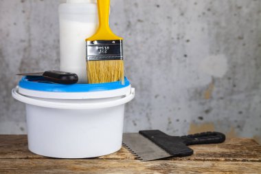 Öğeleri gri bir duvara ev ya da ofis tadilat için. Boya ve masanın üzerine fırça.