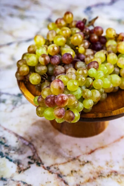 Grapes in a wooden bowl on a marble table.