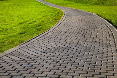 Parktaki taş patika ve yeşil çimenlik. Yürümek için güzel bir yaz parkı..