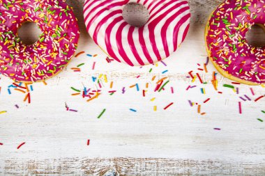 Ahşap arka plan üzerinde pembe çörek. Lezzetli tatlı.