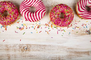 Ahşap arka plan üzerinde pembe çörek. Lezzetli tatlı.