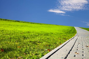 Taş yol park, mavi gökyüzü ve yeşil çim. Yürüyüş için güzel yaz Şehir Parkı.