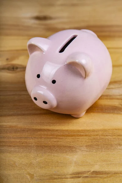 Pink pig money box on a wooden background close up.
