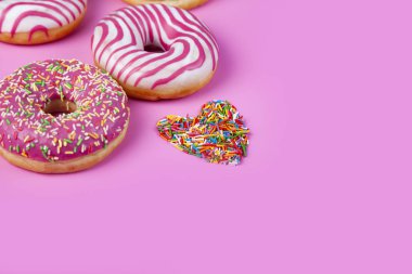 Çörek ve şekerleme kalp pembe bir arka plan üzerinde. Lezzetli tatlı.