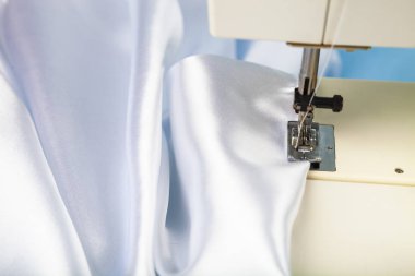 Dikiş makinesi ve beyaz saten kumaş yakın çekim