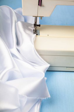 Dikiş makinesi ve beyaz saten kumaş yakın çekim