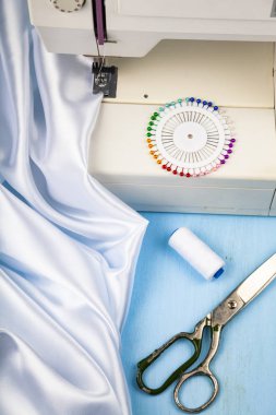 Dikiş makinesi ve beyaz saten kumaş yakın çekim