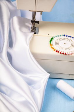 Dikiş makinesi ve beyaz saten kumaş yakın çekim
