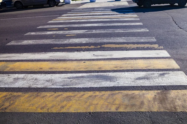 Pedestrian crossing with white and yellow stripes close-up.