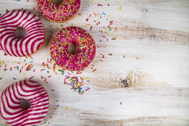 Ahşap arka plan üzerinde pembe çörek. Lezzetli tatlı.