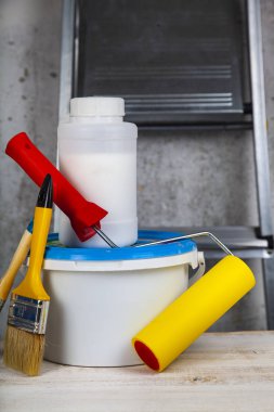 Boya, rulo ve fırça masanın üzerinde. Bir gri duvar ve merdiven karşı ev ya da ofis tadilat için öğeleri.