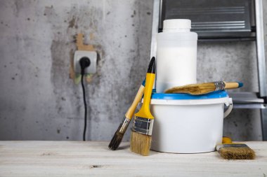 Boya ve masanın üzerine fırça. Bir gri duvar ve merdiven karşı ev ya da ofis tadilat için öğeleri.