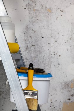 Boya, silindir ve fırçalar bir merdiven üzerinde. Gri bir duvara ev ya da ofis tadilat için öğeleri.