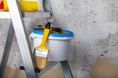 Boya, silindir ve fırçalar bir merdiven üzerinde. Gri bir duvara ev ya da ofis tadilat için öğeleri.