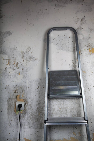 Stepladder on a gray wall background. Repair in the house or office.