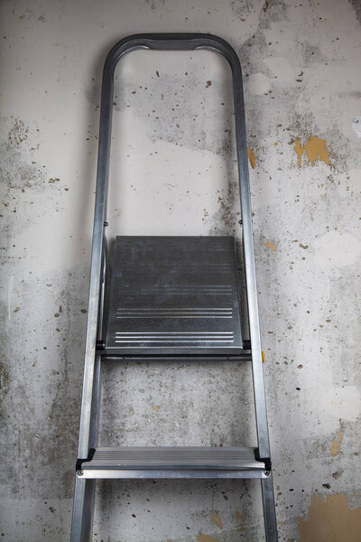 Stepladder on a gray wall background. Repair in the house or office.