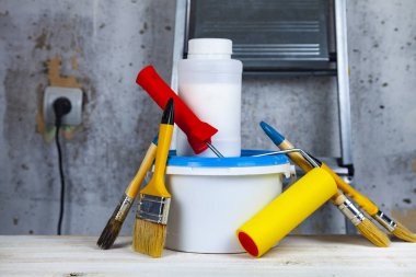 Boya, rulo ve fırça masanın üzerinde. Bir gri duvar ve merdiven karşı ev ya da ofis tadilat için öğeleri.