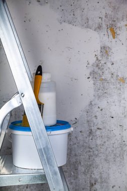 Boya ve fırça bir merdiven üzerinde. Gri bir duvara ev ya da ofis tadilat için öğeleri.