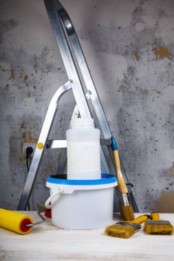 Boya, rulo ve fırça masanın üzerinde. Bir gri duvar ve merdiven karşı ev ya da ofis tadilat için öğeleri.