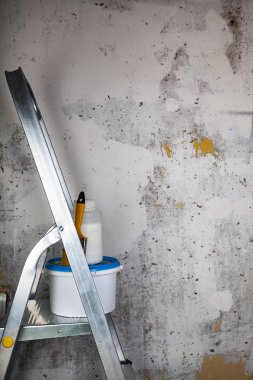 Boya ve fırça bir merdiven üzerinde. Gri bir duvara ev ya da ofis tadilat için öğeleri.