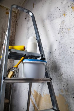 Boya ve fırça bir merdiven üzerinde. Gri bir duvara ev ya da ofis tadilat için öğeleri.