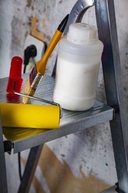 Boya ve fırça bir merdiven üzerinde. Gri bir duvara ev ya da ofis tadilat için öğeleri.