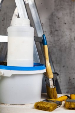 Boya ve fırça bir merdiven üzerinde. Gri bir duvara ev ya da ofis tadilat için öğeleri.