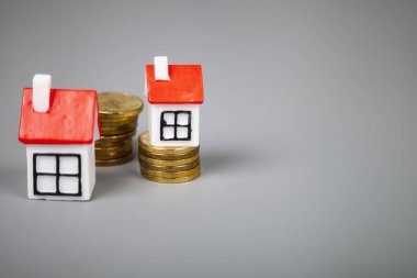 Gri bir arka plan üzerinde paralar küçük evler. Satın almak veya gayrimenkul satış.