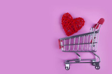 Pembe bir arka plan üzerinde alışveriş sepeti kalbinde. Tatil için alışveriş.