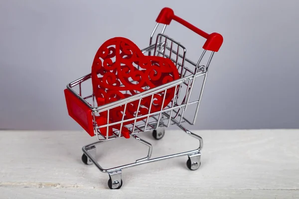 Heart in the shopping cart on a gray background. Shopping for the holiday.