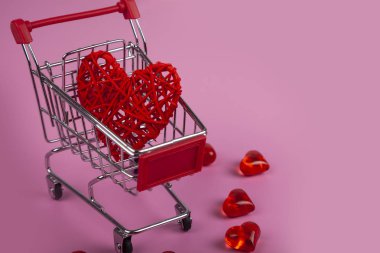 Pembe bir arka plan üzerinde alışveriş sepeti kalbimizde. Tatil için alışveriş.