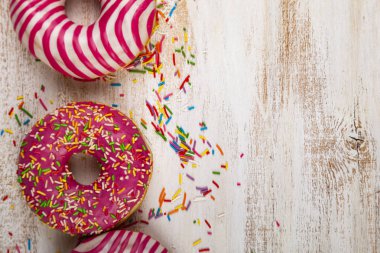 Ahşap arka plan üzerinde pembe çörek. Lezzetli tatlı.