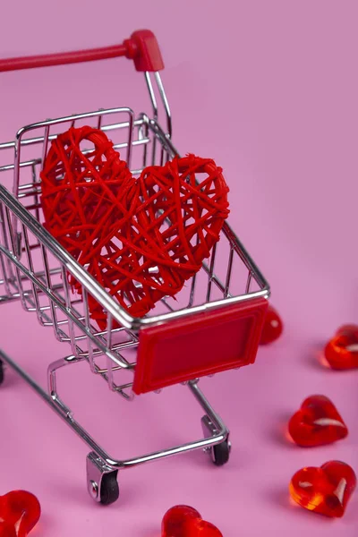 Hearts in the shopping cart on a pink background. Shopping for the holiday.