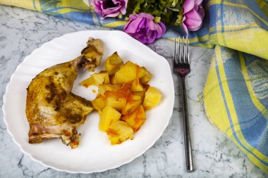 Kızarmış tavuk budu ahşap bir masa üzerinde patates ile. Lezzetli akşam yemeği.