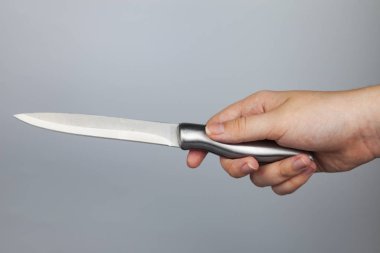 Gri arka plan üzerinde elinde gümüş bıçak.