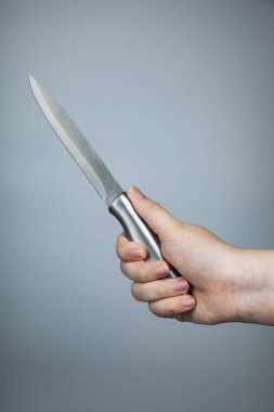 Gri arka plan üzerinde elinde gümüş bıçak.