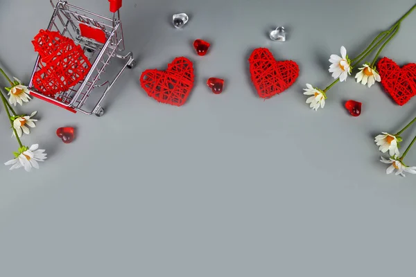 Hearts, flowers and shopping cart on a grey background. Shopping for the holiday.