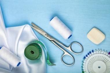 Mavi ahşap arka plan üzerinde dikiş aksesuarları.