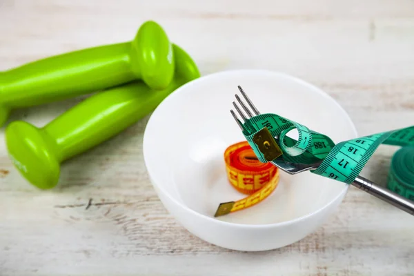 Fork, plate, measuring tape and dumbbells — Stock Photo, Image