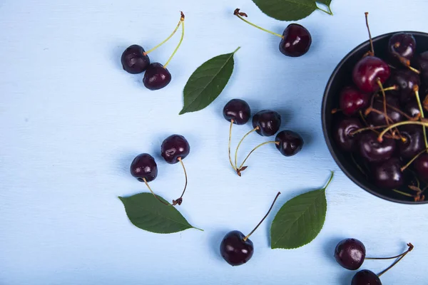 Ripe sweet cherry in a black bowl — Stock Photo, Image