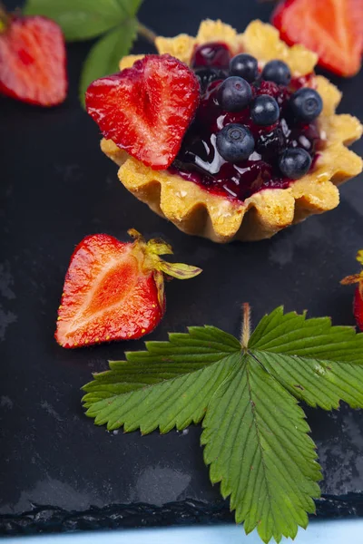 Małe ciasto jagodowe i dojrzałe jagody — Zdjęcie stockowe