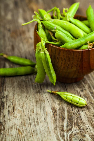 Groene erwten in een houten schaal. — Stockfoto