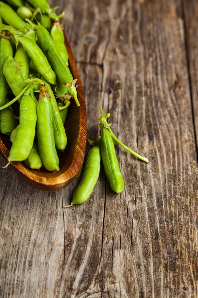 Groene erwten in een houten schaal. — Stockfoto