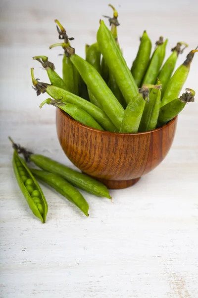 Green peas in a wooden bowl. — Stock Photo, Image