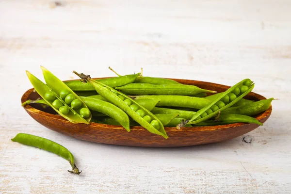 Groene erwten in een houten schaal. — Stockfoto