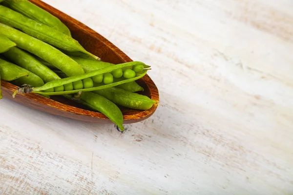 Groene erwten in een houten schaal. — Stockfoto