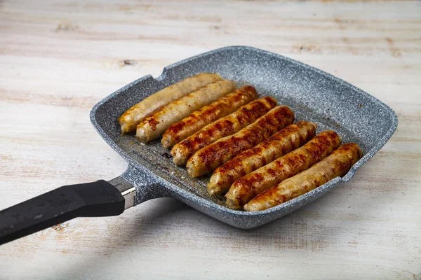 Kupaty in a frying pan on a wooden table. Stock Photo by ©Enika100 284381520