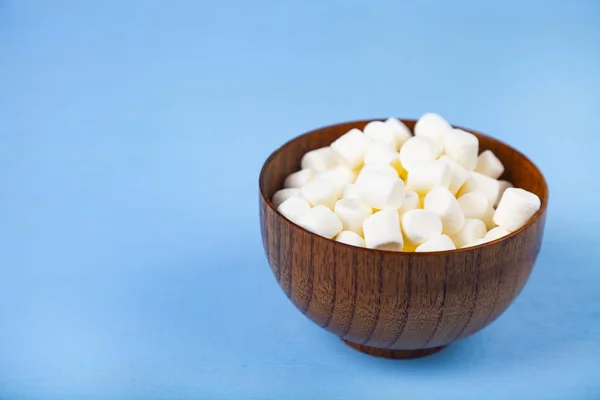 Marshmallow i en skål på en blå trä bakgrund — Stockfoto