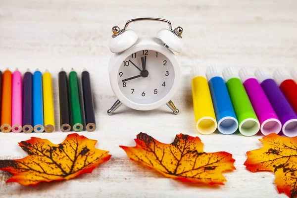 Jelölők, ceruzák, ébresztőóra és őszi levelek — Stock Fotó